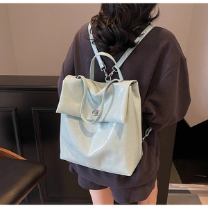 Detalle de mochila verde menta con patrón de cocodrilo y hebilla plateada en modelo