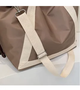 Detail of adjustable woven shoulder strap and silver metal hooks on brown tote bag