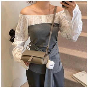 Detailed view of gray crossbody bag with pebble leather texture and fuzzy ball charm