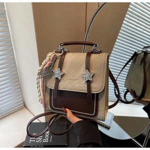 Détail du sac à dos en toile kaki et cuir marron avec des accents métalliques en forme d'étoile