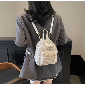 Détail d'un mini sac à dos en tweed ivoire chic porté par un mannequin en bureau