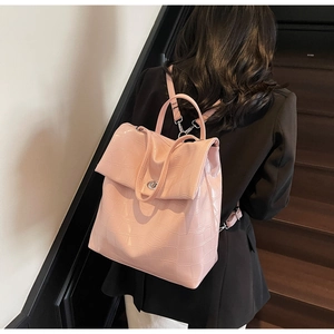 Detalle de mochila rosa con textura de cocodrilo y cierre giratorio sobre la modelo