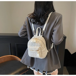 Vue arrière d'un mini sac à dos chic en tweed crème porté avec un blazer gris élégant