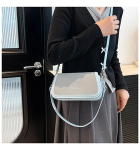 Detail of light blue woven crossbody bag with silver hardware and adjustable strap