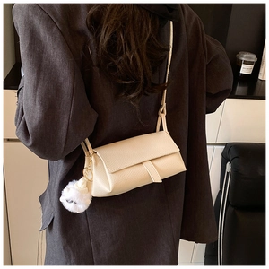 Detail of creamy white pebble grain leather crossbody bag with fluffy pom-pom charm
