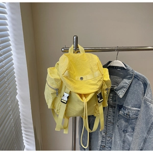 Detail of bright yellow nylon backpack with pleated texture and side zipper pockets