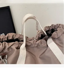Detail of the drawstring closure and sturdy white webbing handles on the brown nylon tote bag