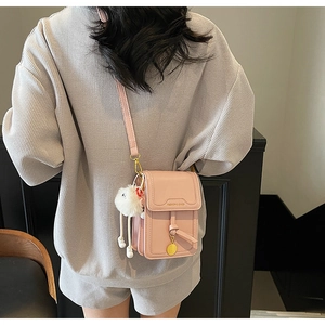 Detailed back view of a pink mini crossbody phone bag with a white fuzzy pompom charm