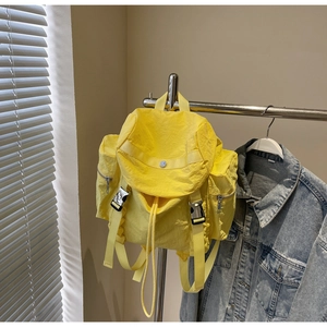 Detail of yellow nylon backpack with drawstring closure and silver buckle pockets