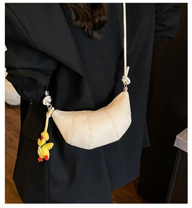 Chic beige textured leather crescent bag with a cute yellow duck pendant and knotted strap