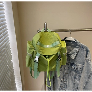 Detailed view of green nylon backpack with buckle closure and drawstring top for daily use