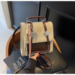 Détail du sac à dos en toile beige et cuir marron avec breloque raquette de tennis et bijoux