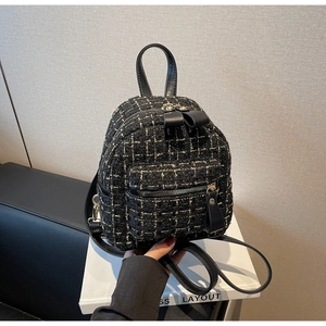 Détail du sac à dos en tweed noir avec fermeture dorée et poignée en cuir élégante