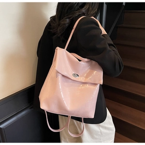 Detalle de mochila rosa claro con estampado de cocodrilo y cierre de giro en metal plateado