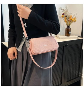 Detail of pink shoulder bag featuring woven texture flap and silver metal hardware