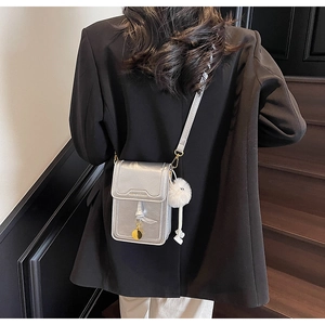 Silver metallic crossbody phone bag with fluffy pompom detail worn by a model