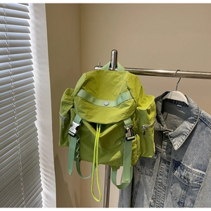 Detail of lime green nylon backpack with silver metal buckles and drawstring closure