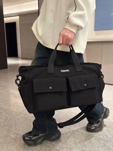 Large black nylon travel bag with wet-dry separation shown in a lifestyle pose