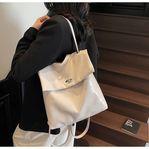Detalle de mochila blanco crema con relieve de cocodrilo y cierre de giro plateado