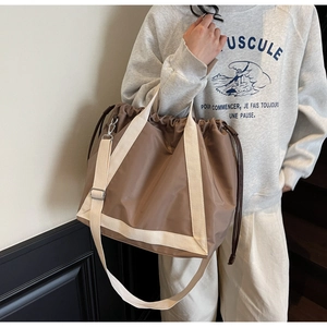 Detail view of large coffee nylon tote bag with drawstring closure and cream handles