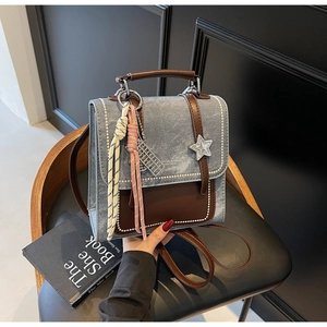 Détail d'un sac à dos en denim bleu et cuir marron avec pendentif étoile sur chaise