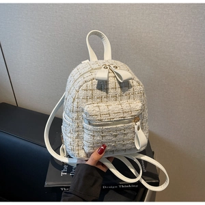 Détail du sac à dos en tweed blanc avec tissage doré et tirette de zip en ruban