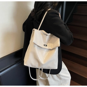 Detalle de mochila beige con patrón de cocodrilo y cierre de giro metálico frontal