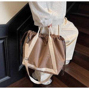 Detail of a large drawstring tote bag with contrast webbing straps in a street style view