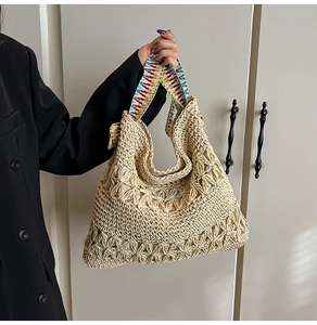 Détail d'un sac cabas en paille tissé avec motifs ajourés et bandoulière bohème colorée