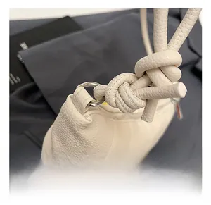 Close-up of white lychee pattern leather handbag with knot strap and silver hardware