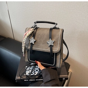 Détail du sac à dos en toile grise et cuir noir avec boucles étoiles et lettrage
