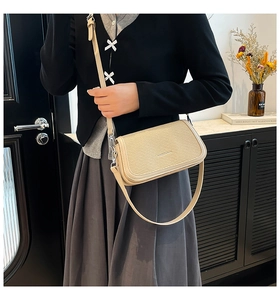 Close-up of beige woven texture crossbody bag with adjustable strap and front flap