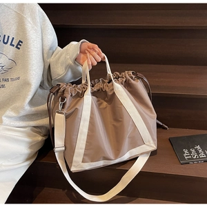Detail of taupe drawstring tote bag with adjustable shoulder strap and canvas handles