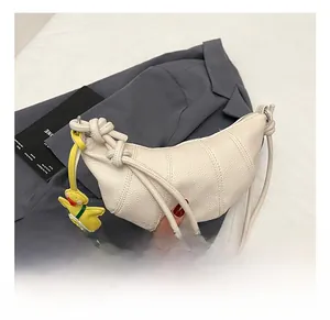 Detail showing white lychee texture half-moon handbag with knot design and yellow duck charm