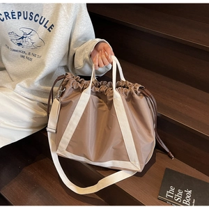 Detail of earth brown nylon tote bag with drawstring closure and white canvas straps