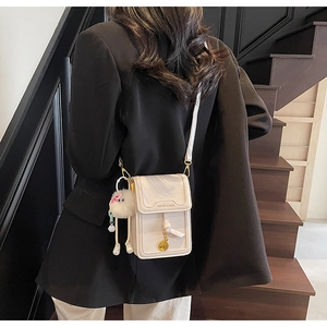 Detail of beige PU leather square phone bag with plush charm and gold buckle