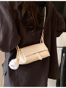 Chic cream rectangle crossbody bag in pebble leather worn by model with plush charm