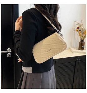 Detail of beige woven crossbody bag with leather trim and silver metal buckle