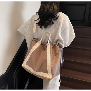 Detailed back view of a large khaki nylon tote bag with drawstring closure and webbed straps