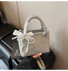 Detail of grey lychee leather bucket bag with pearl bow and white ribbon decor