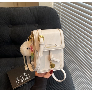 Detail of cream PU leather crossbody bag with gold pendant and plush charm on side