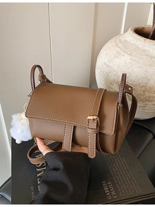 Vintage brown crossbody flap bag with pebble leather texture and plush ball charm