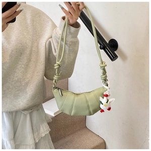 Detail of light green avocado leather crescent bag with gathered texture and duck charm