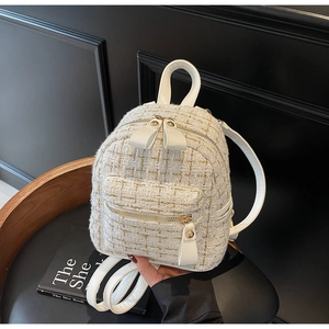 Détail d'un mini sac à dos en tweed blanc montrant la texture tissée et les doubles zips