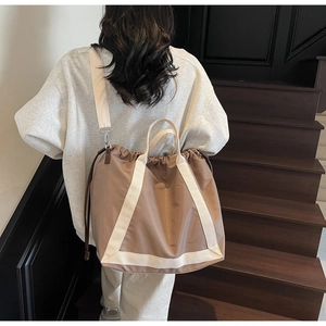 Close-up of lightweight brown nylon tote bag featuring wide cream-colored woven straps