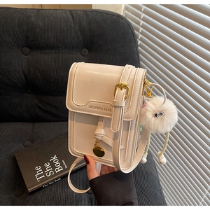Detail of cream white leather mini bag with gold hardware and plush charm pendant