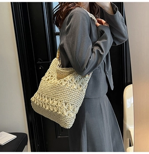 Détail du sac cabas beige crocheté à la main avec motifs floraux et anneau métallique