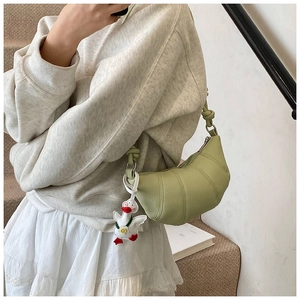 Detail of light green crescent bag with lychee texture and cute duck charm accessory