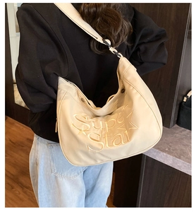 Détail d'un sac demi-lune beige avec broderie Super Star et bandoulière large