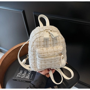 Gros plan d'un mini sac à dos en tweed blanc avec fils dorés et poignée en cuir